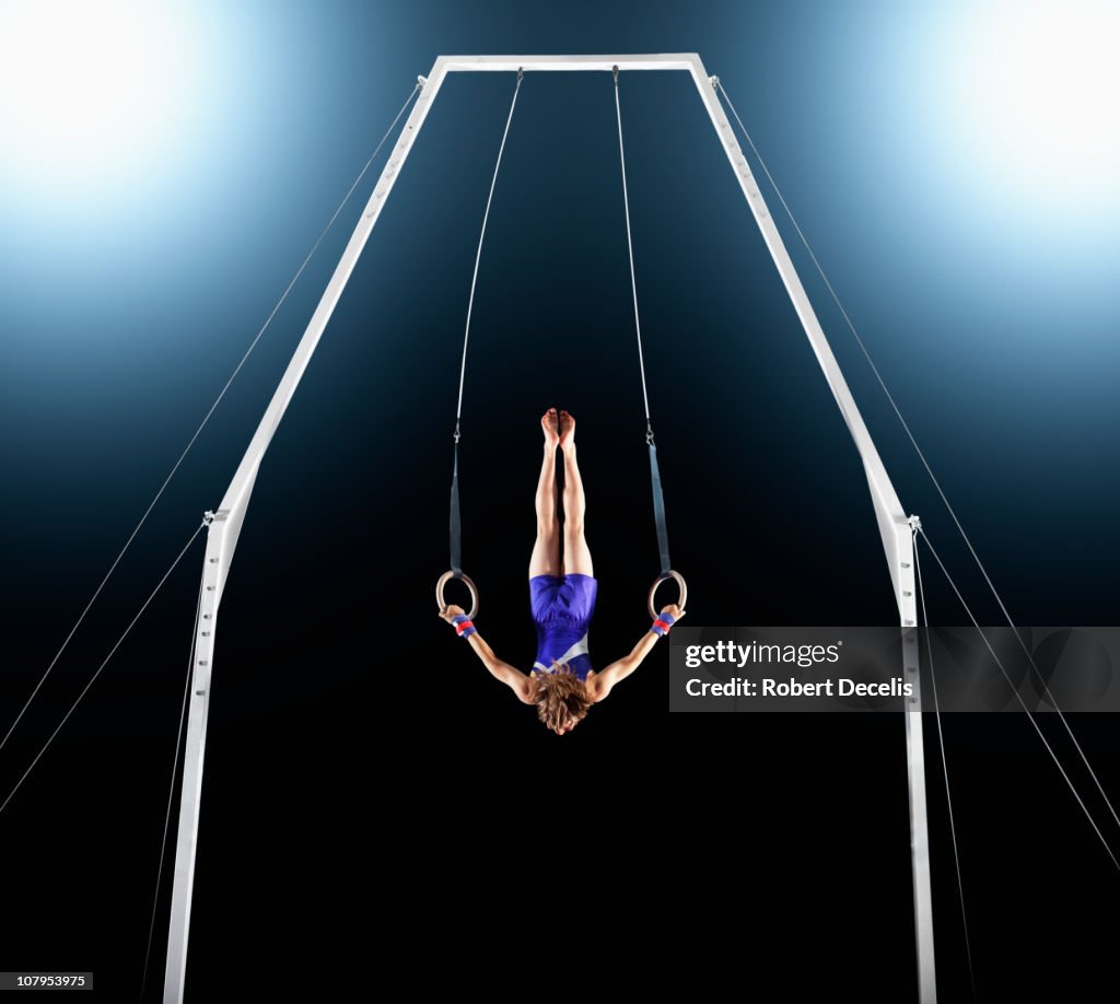 Male gymnast upside down performing on rings