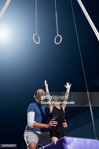 trainer assisting young male gymnast - gymnastics equipment stock pictures, royalty-free photos & images