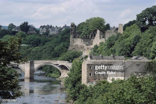 General view of the partial ruins of Barnard Castle and the country bridge which crosses the river Tees, Castle Bernard, Teesdale, County Durham,...
