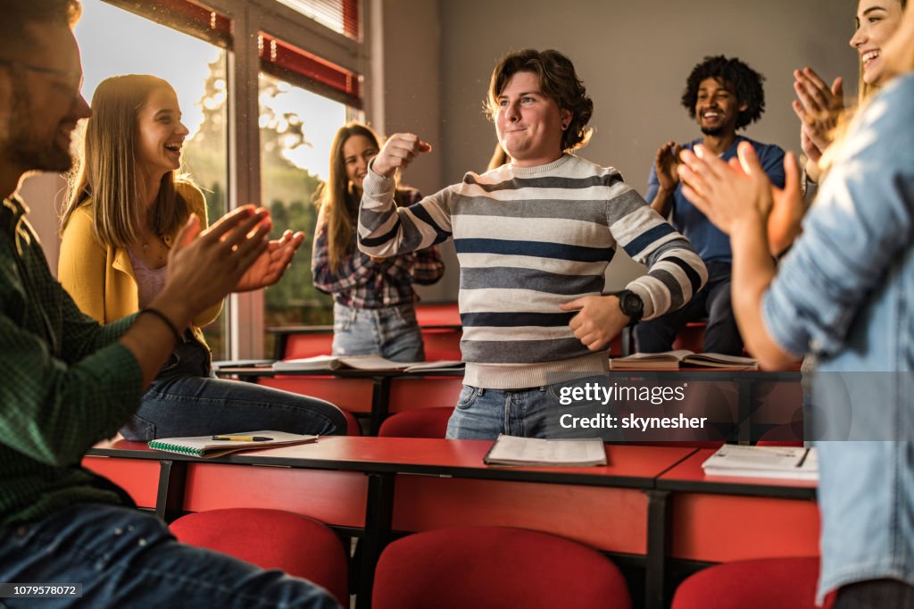 Junge Studenten applaudieren ihre Freundin im Klassenzimmer.