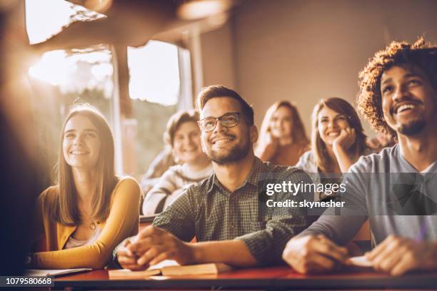 estudiantes felices escuchando a un profesor en el aula. - edificio público fotografías e imágenes de stock