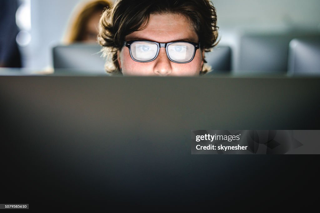 Male student learning a lecture over desktop PC at computer lab.