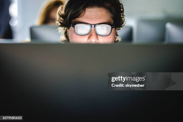 male student learning a lecture over desktop pc at computer lab. - olhos abertos imagens e fotografias de stock