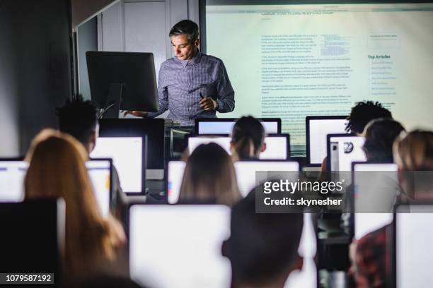 professore adulto medio che insegna una lezione dal pc desktop al laboratorio informatico. - educazione foto e immagini stock