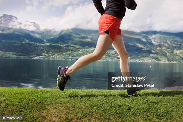 legs of woman jogging against sea and mountains - running shorts stockfoto's en -beelden