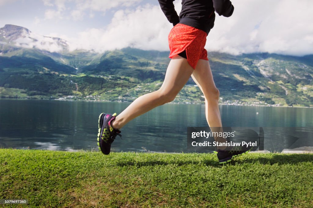 Legs of woman jogging against sea and mountains