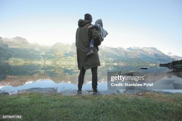 father with daughter standing on lakes edge - landskap stockfoto's en -beelden