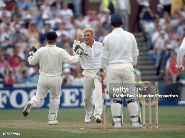 Shane Warne of Australia celebrates with wicketkeeper Ian Healy after bowling England batsman Mike Gatting for 4 during the second day of the 1st...