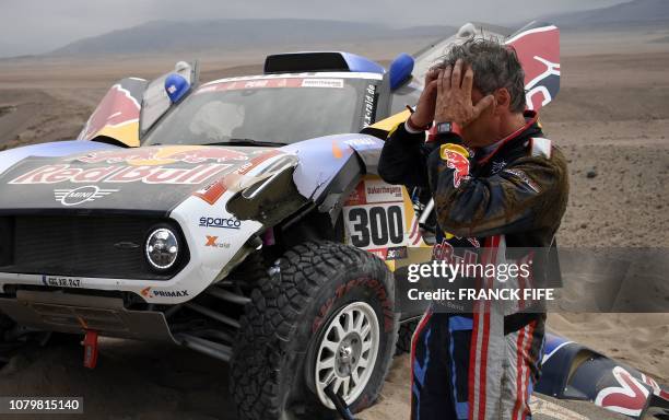 Mini's Spanish driver Carlos Sainz of Spain gestures next to his car after stopping due to a crash during Stage 3 of the Dakar 2019 between San Juan...