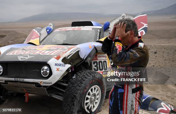 Mini's Spanish driver Carlos Sainz gestures next to his car after the front suspension on his Mini broke during the Stage 3 of the Dakar Rally...
