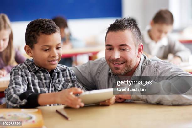 boy showing teacher schoolwork on tablet computer - teacher desk foto e immagini stock