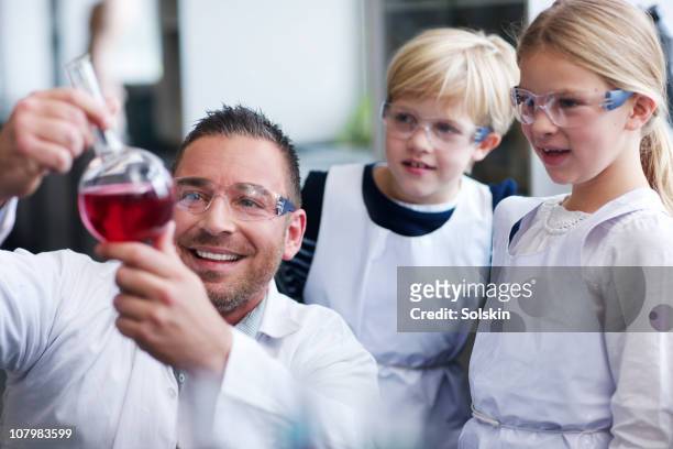 teacher with boy and girl in school laboratory - children in a lab stock pictures, royalty-free photos & images