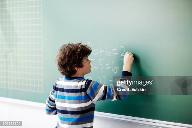 boy writing on board in school class - mathematics stockfoto's en -beelden