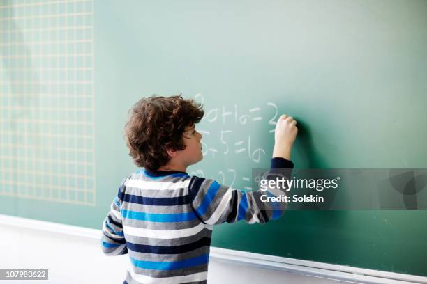 boy writing on board in school class - mathematics stock pictures, royalty-free photos & images