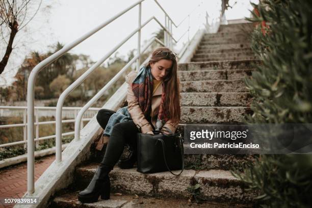 jonge vrouw zoeken op haar tas - vinden stockfoto's en -beelden