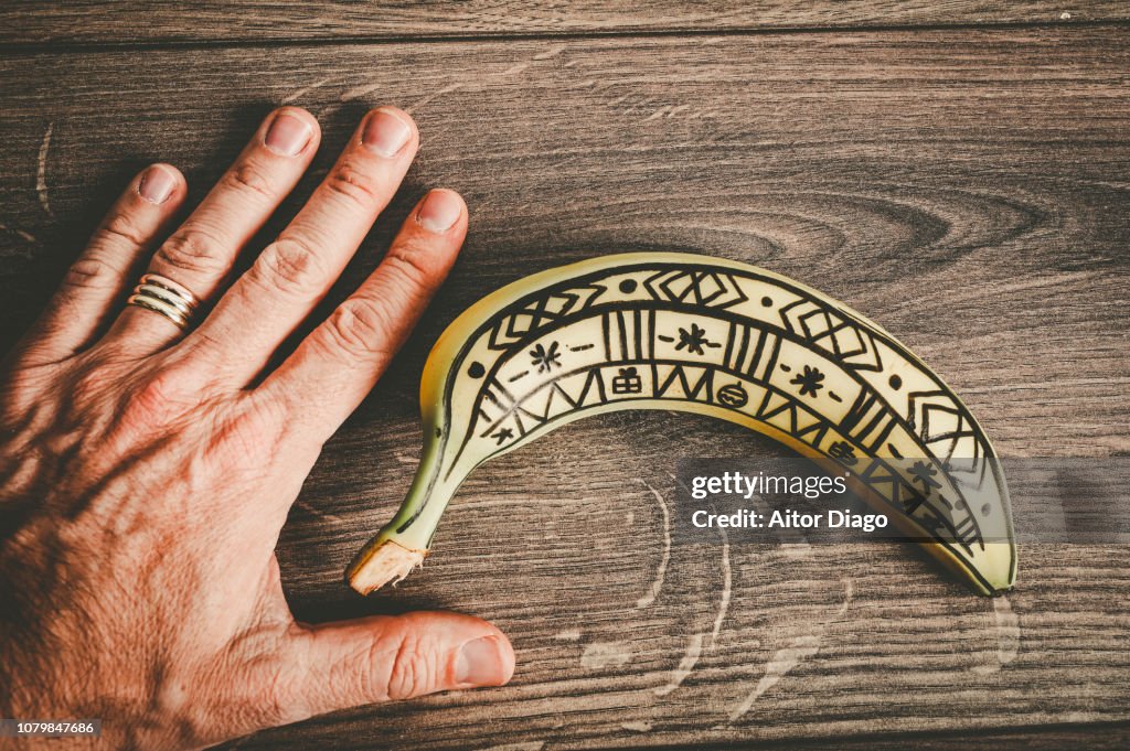 Hand close to a painted banana. Conceptual nature
