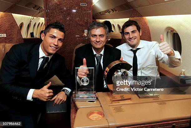 Cristiano Ronaldo, head coach Jose Mourinho and Iker Casillas of Real Madrid pose with their trophies during their flight back after the FIFA Ballon...