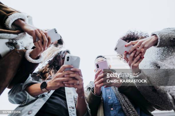 group of friends in the street with smartphone - medios de comunicación fotografías e imágenes de stock