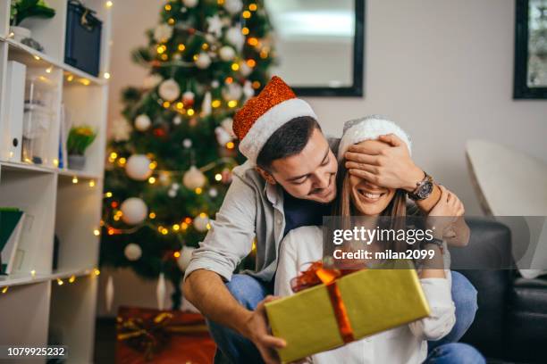 young couple celebrating christmas - christmas gift exchange stock pictures, royalty-free photos & images