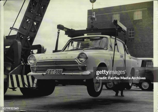 The car being lifted.A newly developed battery powered electro-magnet was demonstrated today at the Union Carbide plant at Roseberry. It is powered...