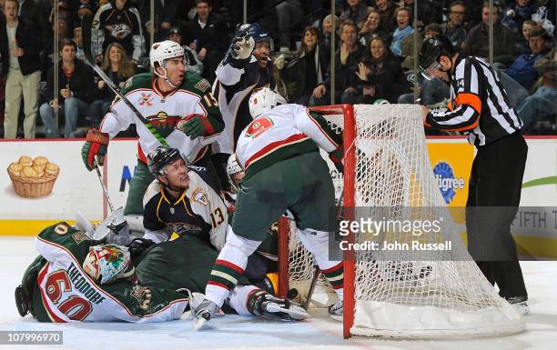 Nick Spaling of the Nashville Predators gets the puck in the net against goalie Jose Theodore of the Minnesota Wild as referee David Banfield eyes...