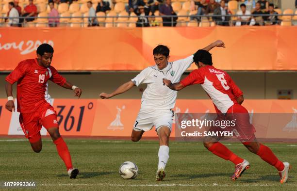 Odil Ahmedov of Uzbekistan kicks the ball sandwiched between Mohammed Ahmed Juma and Hadam Ismail al-Kamali of the United Arab Emirates during their...