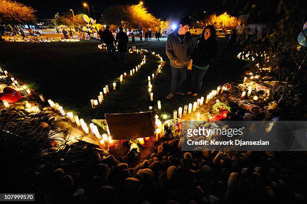People look at a makeshift memorial that continues to grow in front of University Medical Center, for those killed and wounded during an attack on...