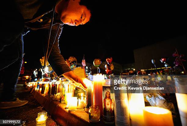 People light candles at a makeshift memorial that continues to grow in front of University Medical Center, for those killed and wounded during an...