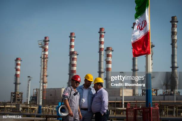 Employees stand near an Iranian national flag at the new Phase 3 facility at the Persian Gulf Star Co. Gas condensate refinery in Bandar Abbas, Iran,...