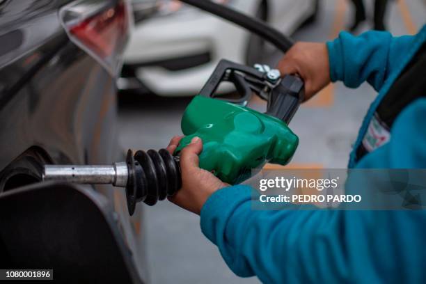 Pemex petrol station attendant fills up the tank of a car in Mexico City on January 10, 2019. - President Andres Manuel Lopez Obrador urged Mexicans...