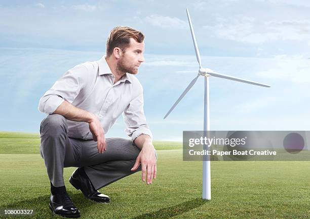 business man looking at modern windmill - crouching ストックフォトと画像