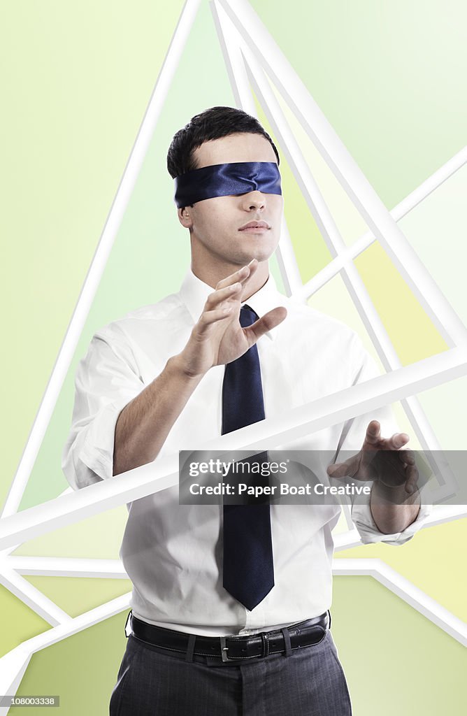 Business man blind folded, in abstract maze