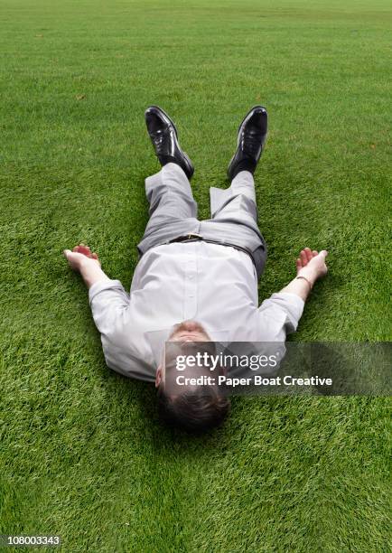 man lying down on a field of bright green grass - newbusiness stock pictures, royalty-free photos & images