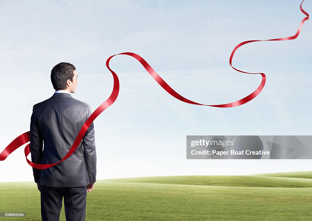 Business man looking at floating red ribbon