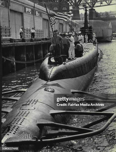 Crew member checks the flag-flying at half-mast in memory of President Kennedy while others clear the deck as the U.S. Submarine Archerfish berths at...