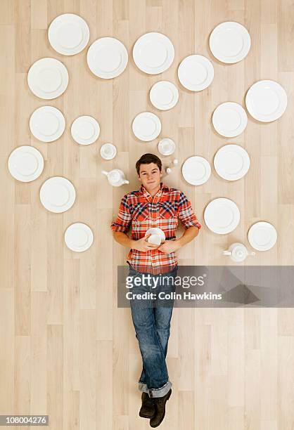 man laying on floor with crockery thought bubbles - lying down stockfoto's en -beelden