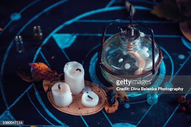 alchemist workplace heder with lab burner, potion bottles, candles, and chalk pentagram. magical still life on a dark background with copy space. - wicca stock-fotos und bilder