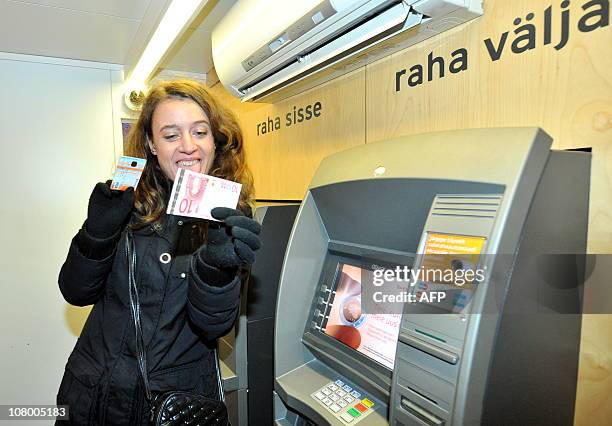 Estonian woman receives her first euro note from the ATM on January 1, 2011 in Tallinn, Estonia. Estonia adopted the European single currency at...