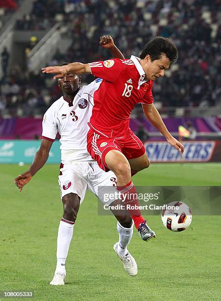 Gao Lin of China is tackled by Mohammed Kasola of Qatar during the AFC Asian Cup Group A match between China P.R and Qatar at Khalifa Stadium on...