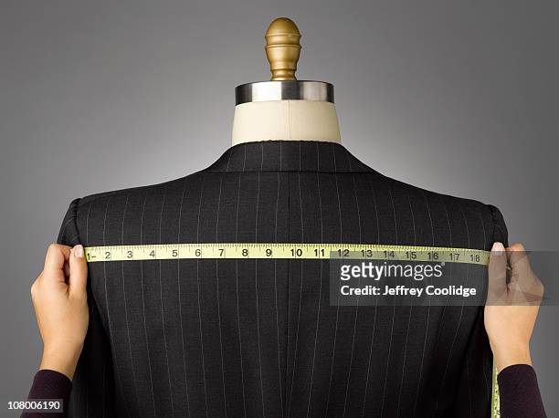 woman measuring jacket on male dress form - sastre fotografías e imágenes de stock