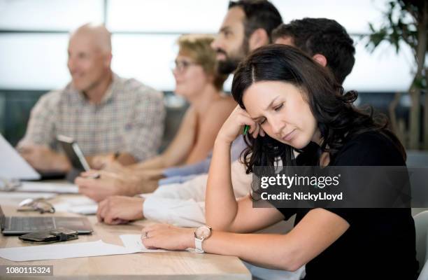 bored businesswoman with colleagues in background at conference table. - woman sleeping table stock pictures, royalty-free photos & images