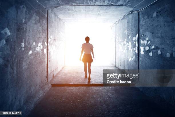 mujer caminando por un oscuro túnel - evasión fotografías e imágenes de stock