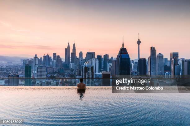 man in a infinity pool with kuala lumpur skyline, malaysia - kuala lumpur foto e immagini stock