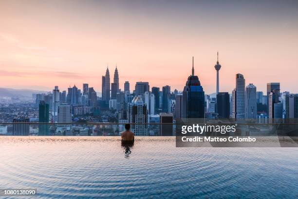 man in a infinity pool with kuala lumpur skyline, malaysia - kuala lumpur city stock pictures, royalty-free photos & images