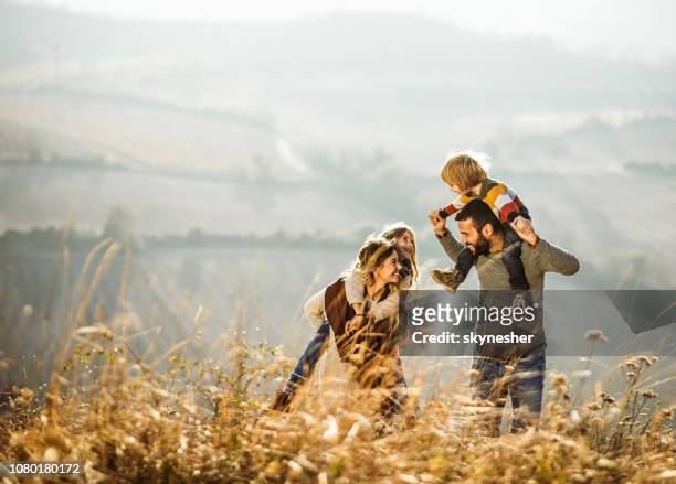 carefree parents having fun with their kids on a field. - carrying on shoulders stock pictures, royalty-free photos & images
