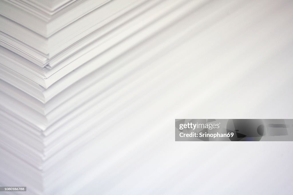 Stack white paper isolated on white background with Clipping Path. Stack of blank paper. Paper stack in bin of offset printing press. - selective focus With noise and blur