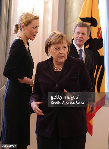 German Chacnellor Angela Merkel looks on as German First Lady Bettina Wulff and German President Christian Wulff gesture during the New Year's...