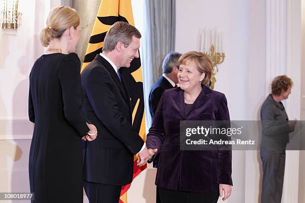 German President Christian Wulff shakes hands with German Chancellor Angela Merkel as German First Lady Bettina Wulff gestures during the New Year's...