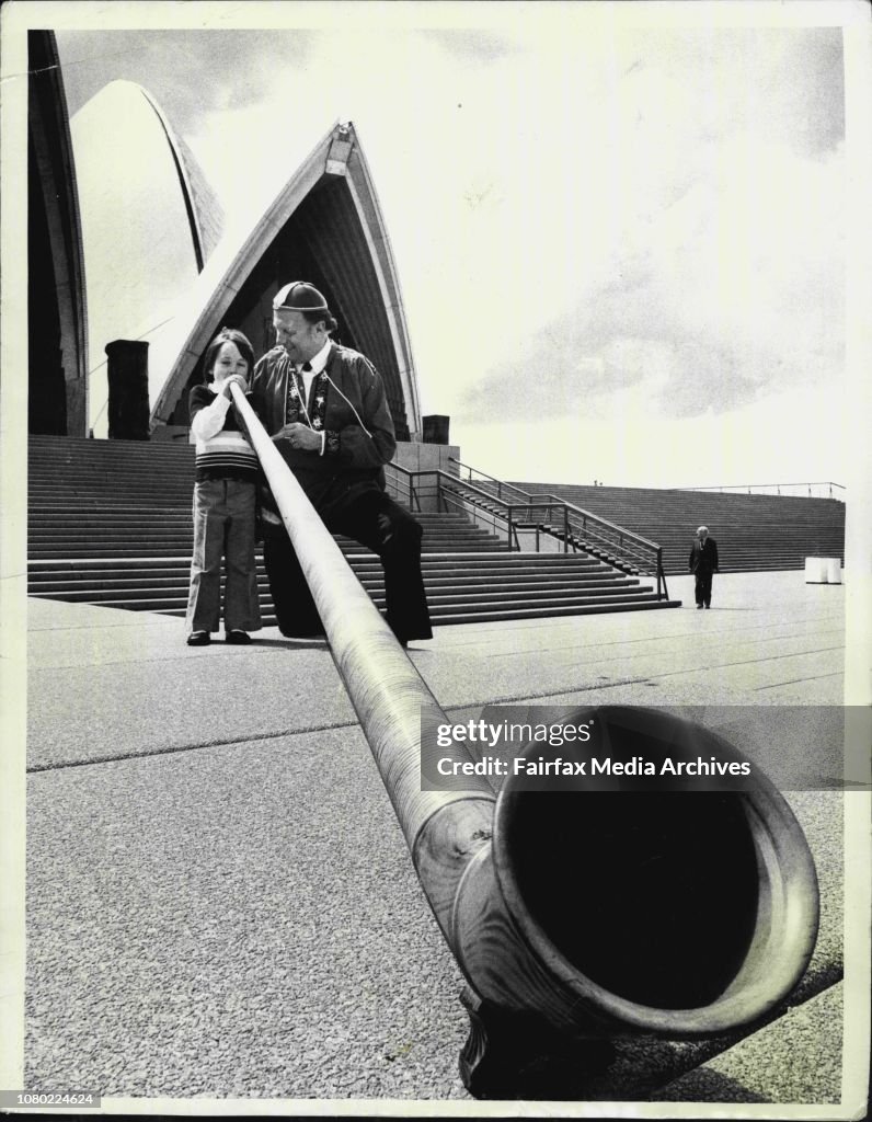 Gino Morelli, of Chatswood, member of the Swiss Yodellers of Sydney, watches as Nichola Barten, 4Â½ if Harbord, takes a deep breath, in an attempt to play a note on the Alphorn, on the steps of the Opera House.Mr. Morelli, will be appearing at he Opera H