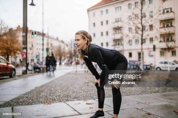 female runner catching her breath during training - runner tired stock pictures, royalty-free photos & images